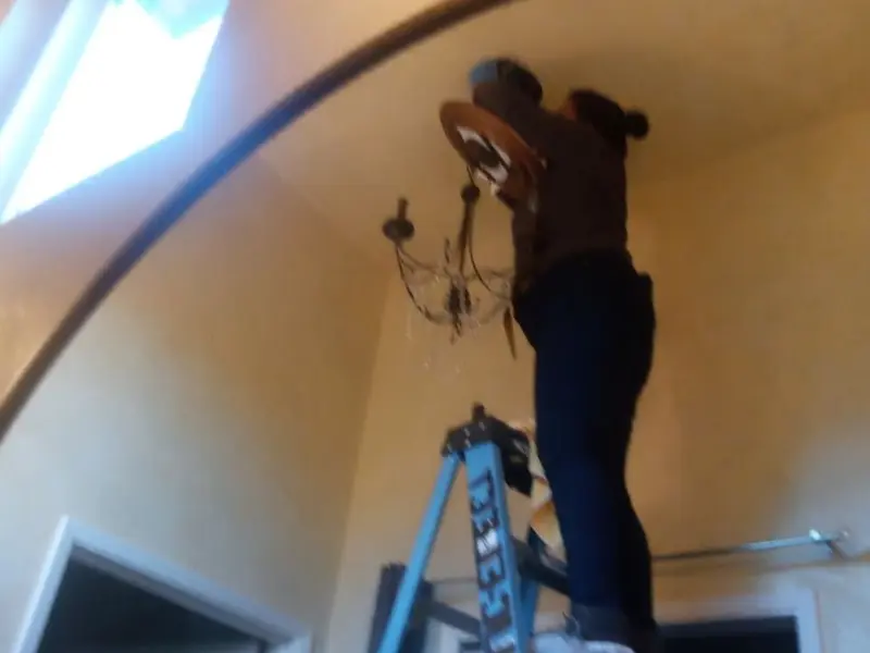 Electrician installing a chandelier in a Socorro residence